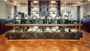 A hotel lobby with a marble reception desk, multiple coffee machines, and a seating area.