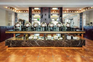 Un vestíbulo de hotel con un mostrador de recepción de mármol, varias máquinas de café y una vitrina de vidrio.