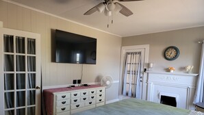 Een slaapkamer met een bed, kaptafel, televisie, ventilator en open haard.