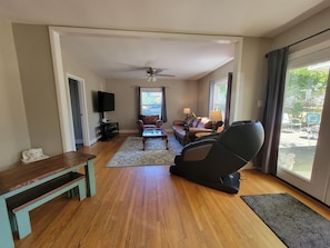 A living room with a sofa, a coffee table, a TV, and a ceiling fan. - Cozy Fayetteville Home - King Bed - Sleeps 5 - Near Downtown (Fayetteville)