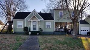 A two-story house with a front porch, a driveway, and a tree in the foreground. - Clean and spacious house in downtown Fayetteville (Fayetteville)