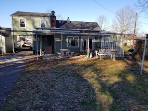A two-story house with a covered porch, a garage, and a small garden area. - Cozy Fayetteville Home - King Bed - Sleeps 5 - Near Downtown (Fayetteville)