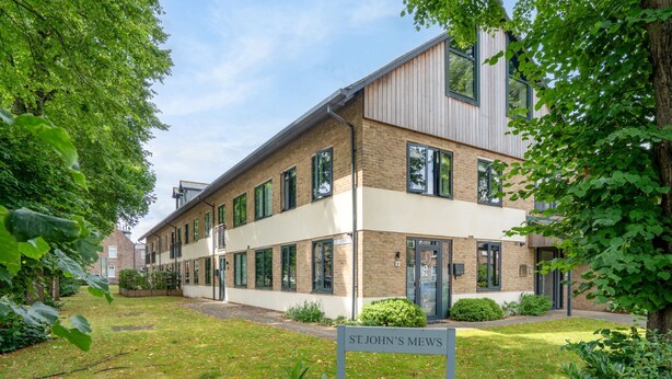 Ein modernes Gebäude mit einem Schild, auf dem 'St. John's Mews' steht.
