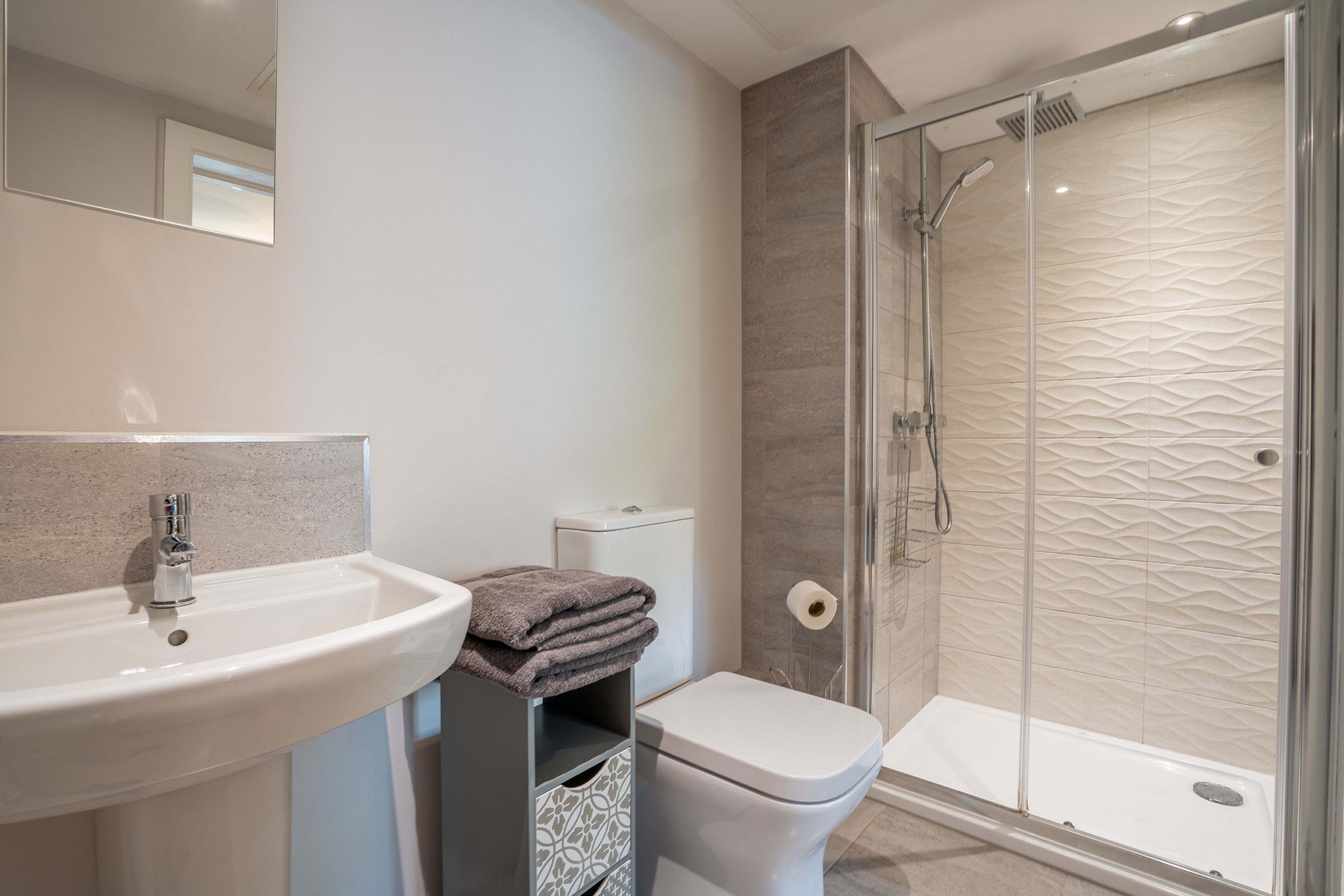 Une salle de bain moderne avec un lavabo, des toilettes et une douche à parois de verre.