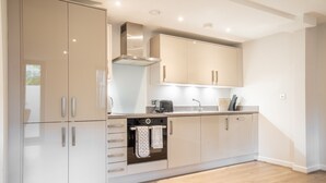 A modern kitchen with white cabinetry, a Bosch range hood, and a built-in oven.