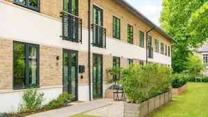 A modern building with large windows, a paved walkway, and a well-maintained garden.
