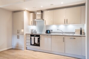 Una cocina moderna con electrodomésticos integrados, una campana extractora de acero inoxidable y un lavabo doble.