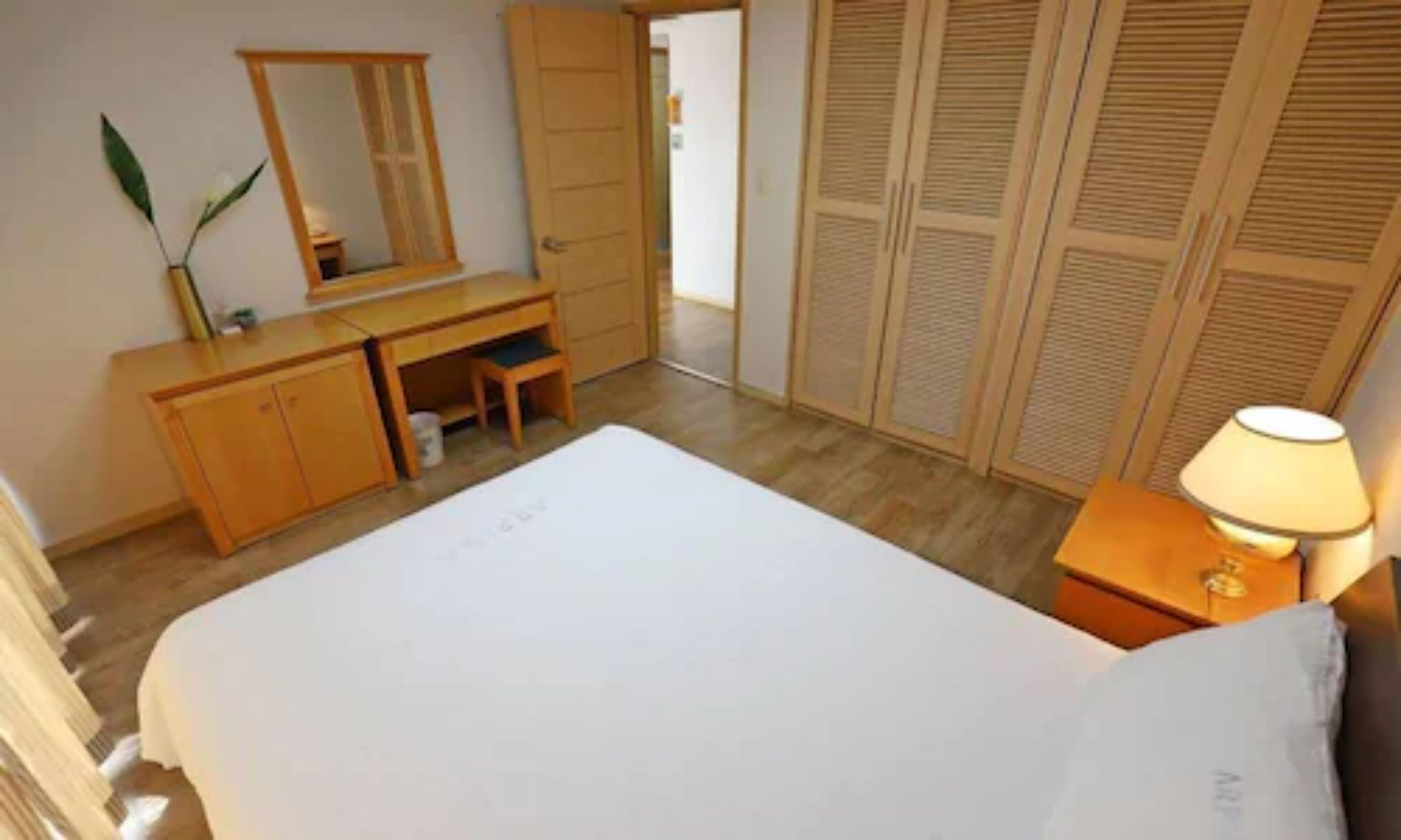Una camera da letto con un letto, una scrivania, una sedia, uno specchio e un armadio.