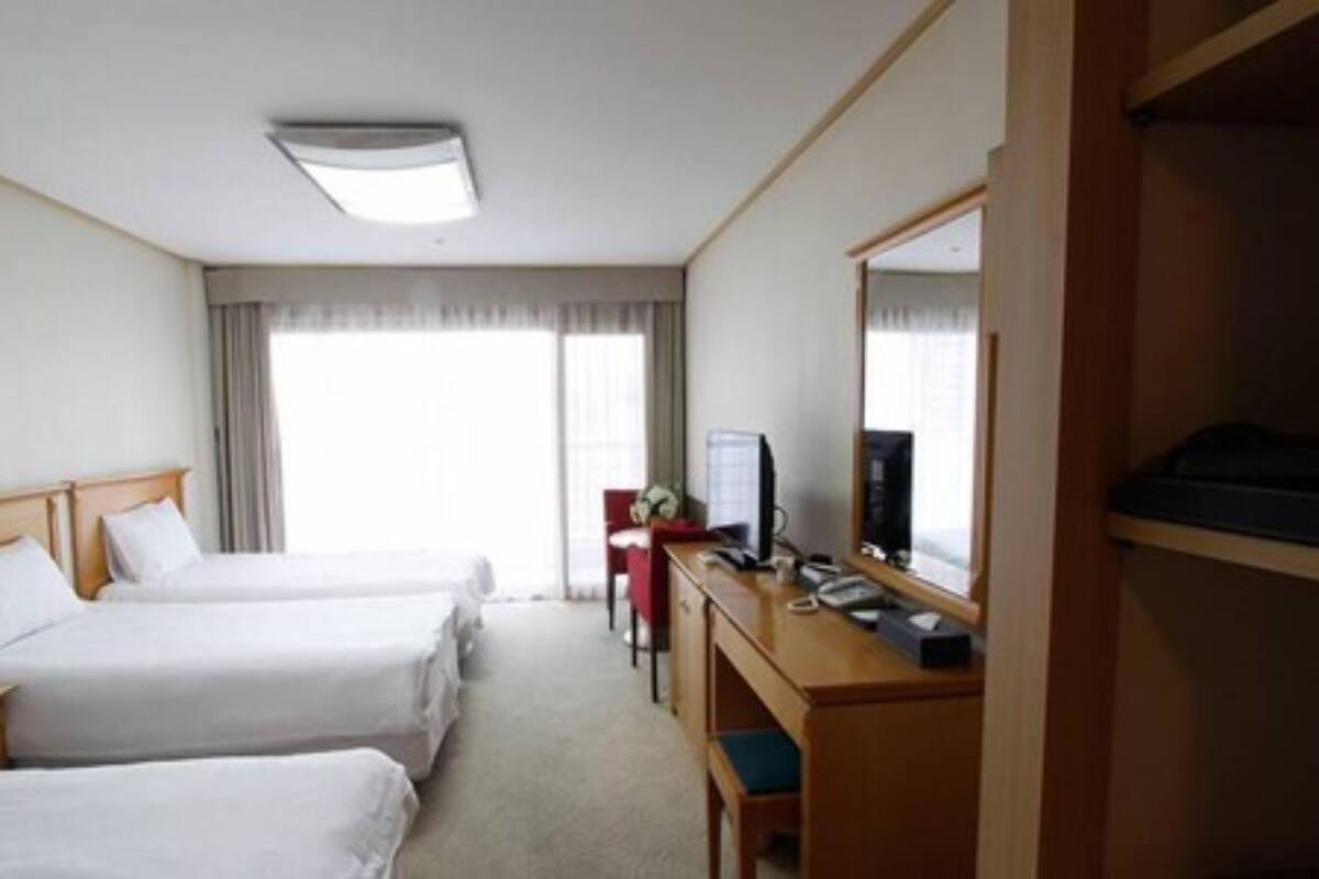 A hotel room with two beds, a desk with a computer, and a large mirror.