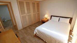 Een slaapkamer met een bed, nachtkastje met lamp en een kledingkast met verstelbare deuren.