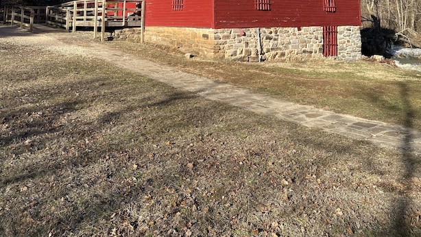 A red barn with a stone foundation, a wooden porch, and a dirt path leading to it. - Shawnee Creek Hideaway - Close to Eminence and the Jacks Fork River! (Winona)