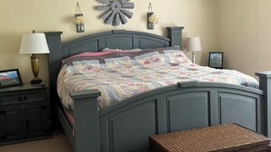 A bedroom with a bed, two bedside tables, a lamp, a decorative wall piece, and a framed picture. - Shawnee Creek Hideaway - Close to Eminence and the Jacks Fork River! (Winona)
