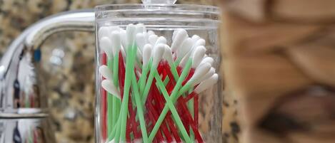 A clear glass container with white and green toothbrushes on a kitchen counter.