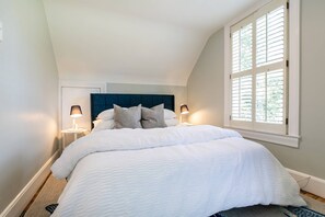 Una camera da letto con un letto grande, due lampade da comodino, una testata scura e una finestra con persiane.