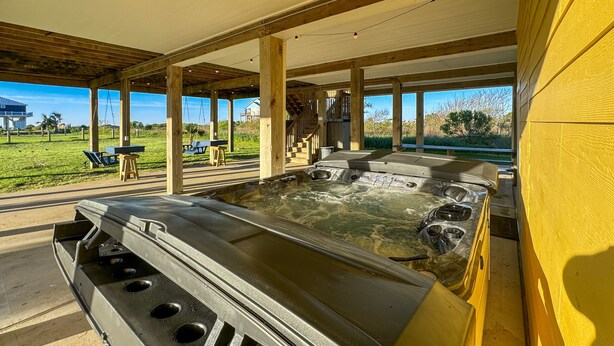 A hot tub area with a wooden deck and outdoor seating. - Family Beach House near Crystal Beach (Gilchrist) · Walk to the Gulf · Hot Tub (Gilchrist)