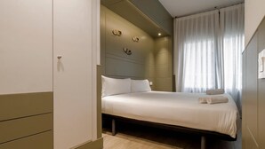 Ein Schlafzimmer mit einem Bett, einem Kleiderschrank und einem Fenster mit Vorh ängen.