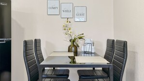A dining area with a glass table, black chairs, a vase with white flowers, and three framed motivational quotes on the wall. - Romantic Guest Suite - Near Downtown & Stadium - High-Speed WiFi (Tampa)