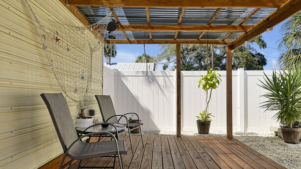 A covered patio with wooden flooring, metal chairs, and potted plants. - Romantic Guest Suite - Near Downtown & Stadium - High-Speed WiFi (Tampa)