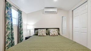 A bedroom with a bed, a nightstand, an air conditioner, and a door. - Romantic Guest Suite - Near Downtown & Stadium - High-Speed WiFi (Tampa)