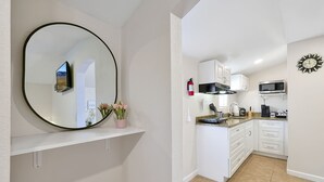 A modern kitchen with white cabinets, a microwave, and a clock on the wall. - Romantic Guest Suite - Near Downtown & Stadium - High-Speed WiFi (Tampa)