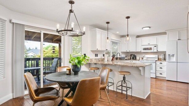 A modern kitchen with white cabinets, a central island, and a dining area with wooden chairs. - Sensationally Furnished *Hot Tub*, Pet Friendly, Game Room w/ Ping Pong, Foosball, Darts, Etc (Vancouver)