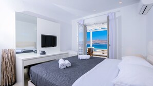 Une chambre d’hôtel moderne dotée d’un grand lit, d’une télévision à écran plat, d’un bureau et d’un balcon offrant une vue sur la mer.