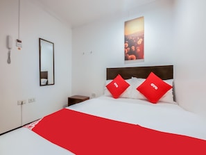 A hotel room with a bed, a nightstand, a mirror, a phone, and a poster on the wall. - Super OYO 856 City Stay Inns Slex Makati (Makati)