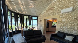 A modern living room with a stone wall, leather sofas, and a wooden floor.