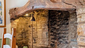 A rustic stone wall with a wooden beam overhead, a bench, and a floor lamp. - Beautifully presented dog friendly holiday cottage in the Cotswolds with a courtyard garden - Heath (Stow-on-the-Wold)