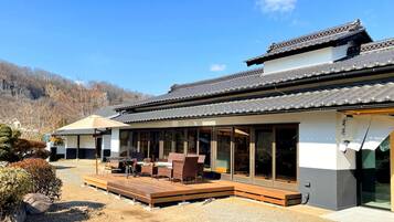 A traditional Japanese-style building with a wooden deck and sliding glass doors.