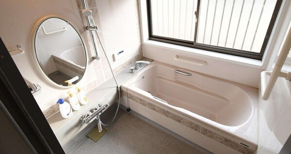 Un baño con bañera, lavamanos, espejo y ventana.