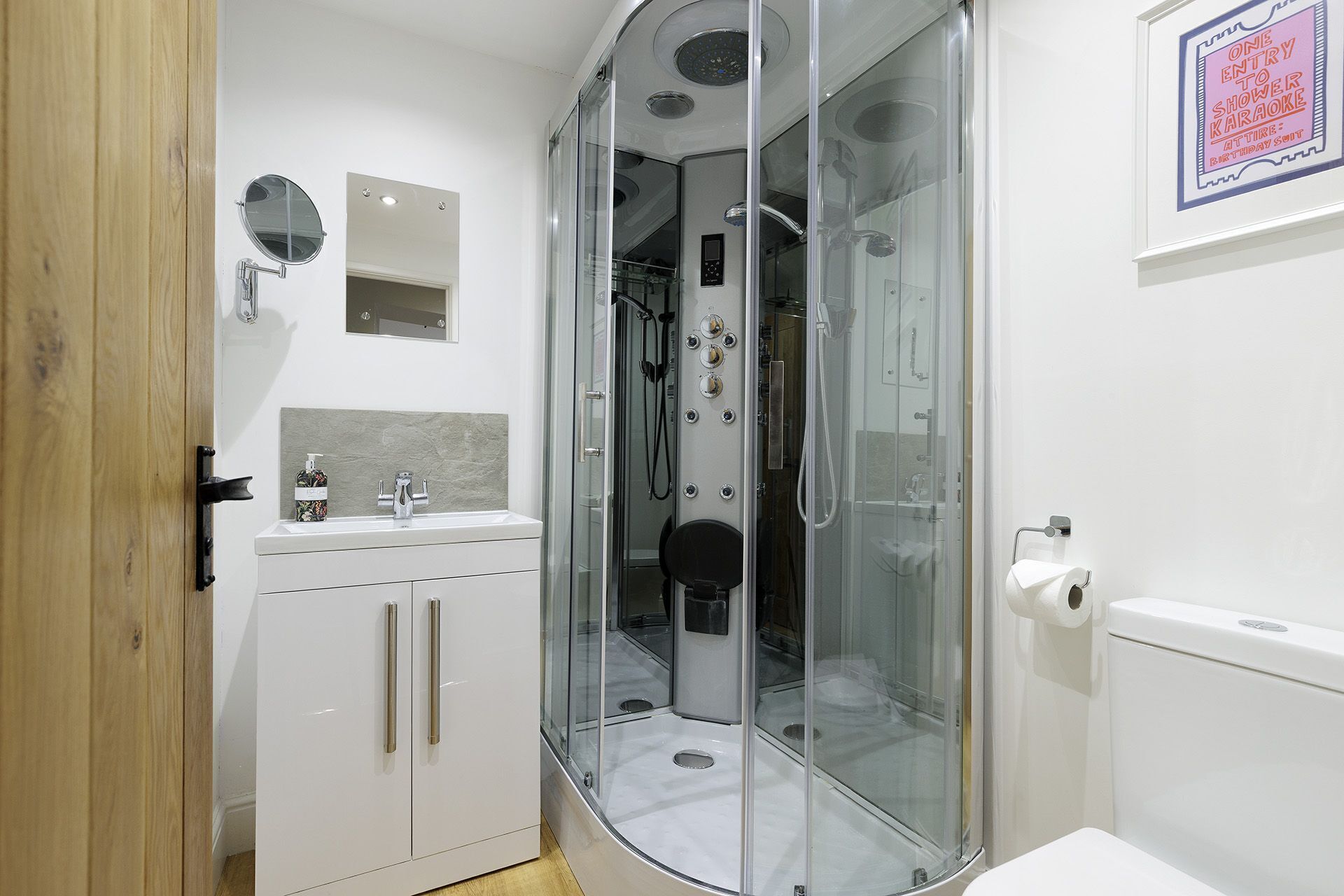 A modern bathroom with a glass-enclosed shower, a sink with a mirror, and a toilet.