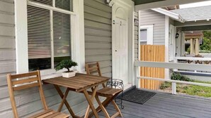 A wooden deck with a table and chairs, a potted plant, and a door leading to another building. - Cozy Studio Bungalow Walk to Armature and Downtown (Tampa)