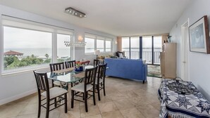 Una habitación amplia con comedor, sofá y vista al mar.