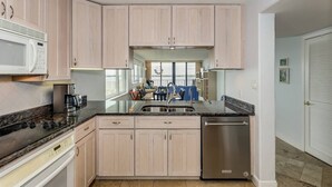 Una cocina moderna con alacenas de madera clara, un refrigerador de acero inoxidable y un microondas integrado.