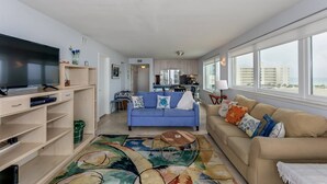 Una sala de estar moderna con un televisor de pantalla plana, un sofá azul, un sofá beige y una alfombra estampada.