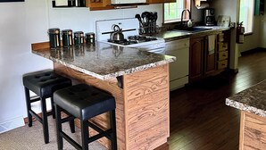 A kitchen with wooden cabinets, a granite countertop, and a built-in island with bar stools.