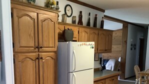 A kitchen with wooden cabinets, a white refrigerator, and a dining area with a table and chairs.