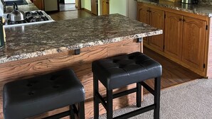A kitchen with granite countertops, wooden cabinets, a refrigerator, and a gas stove.