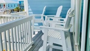 Un pontile in legno con ringhiere bianche e due poltrone Adirondack bianche.
