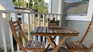 A wooden deck with a table and chairs, a potted plant, and a view of the backyard. - Serenity Bungalow Near Armature Works & Riverwalk (Tampa)