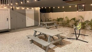 An outdoor patio area with picnic tables, string lights, and a hammock.