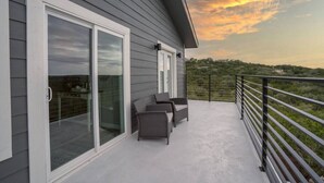 A balcony with a glass door, outdoor furniture, and a view of the landscape.
