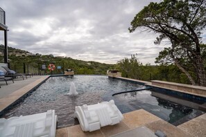 A swimming pool with a waterfall feature, lounge chairs, and a lifebuoy sign.