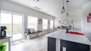 A modern kitchen with a marble island, pendant lights, and a view of the outdoors.