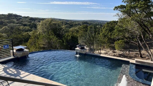 A swimming pool with a view of a forested landscape.