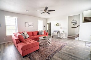 A spacious living room with a red sectional sofa, a round coffee table, and a ceiling fan.