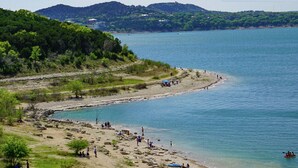 A beach with people, kayaks, and a boat in the water.