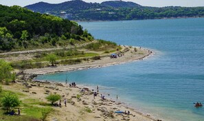 A beach with people, kayaks, and a boat in the water.