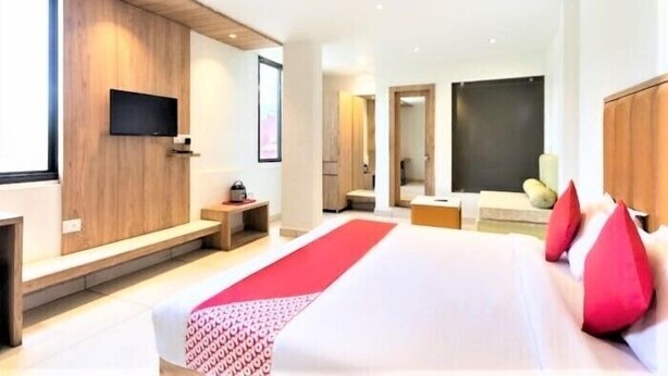 A modern hotel room with a large bed, a flat-screen TV mounted on the wall, and a wooden accent wall. - Hotel Pachmarhi (Pipariya)